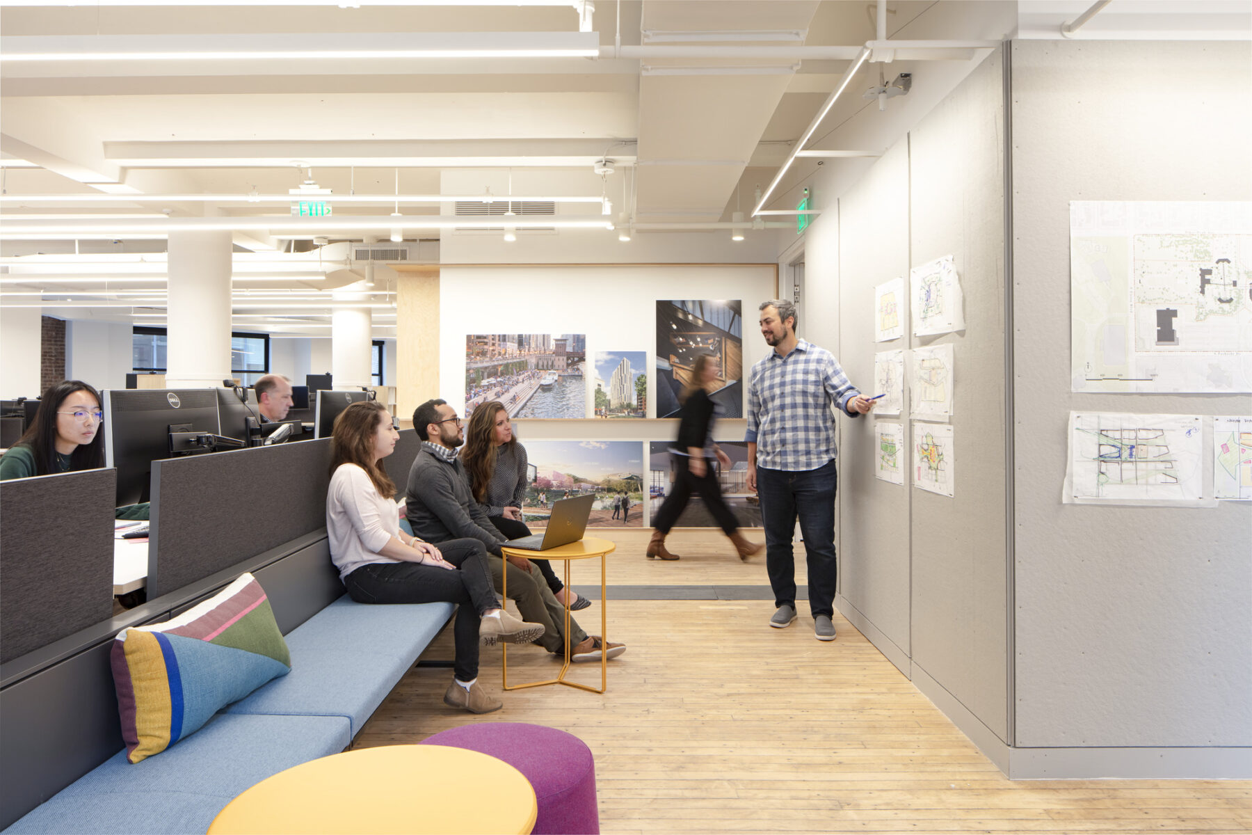 office view with pin up critique and people sitting on bench viewing materials