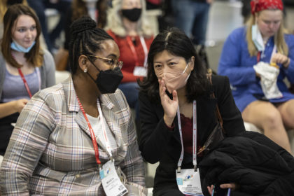 two people talking to each other in the audience at a conference