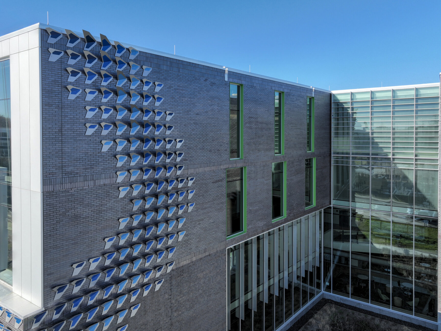 Aerial photograph of building exterior detail showing Water Finds A Way sculpture installed and cascading down from the top floor