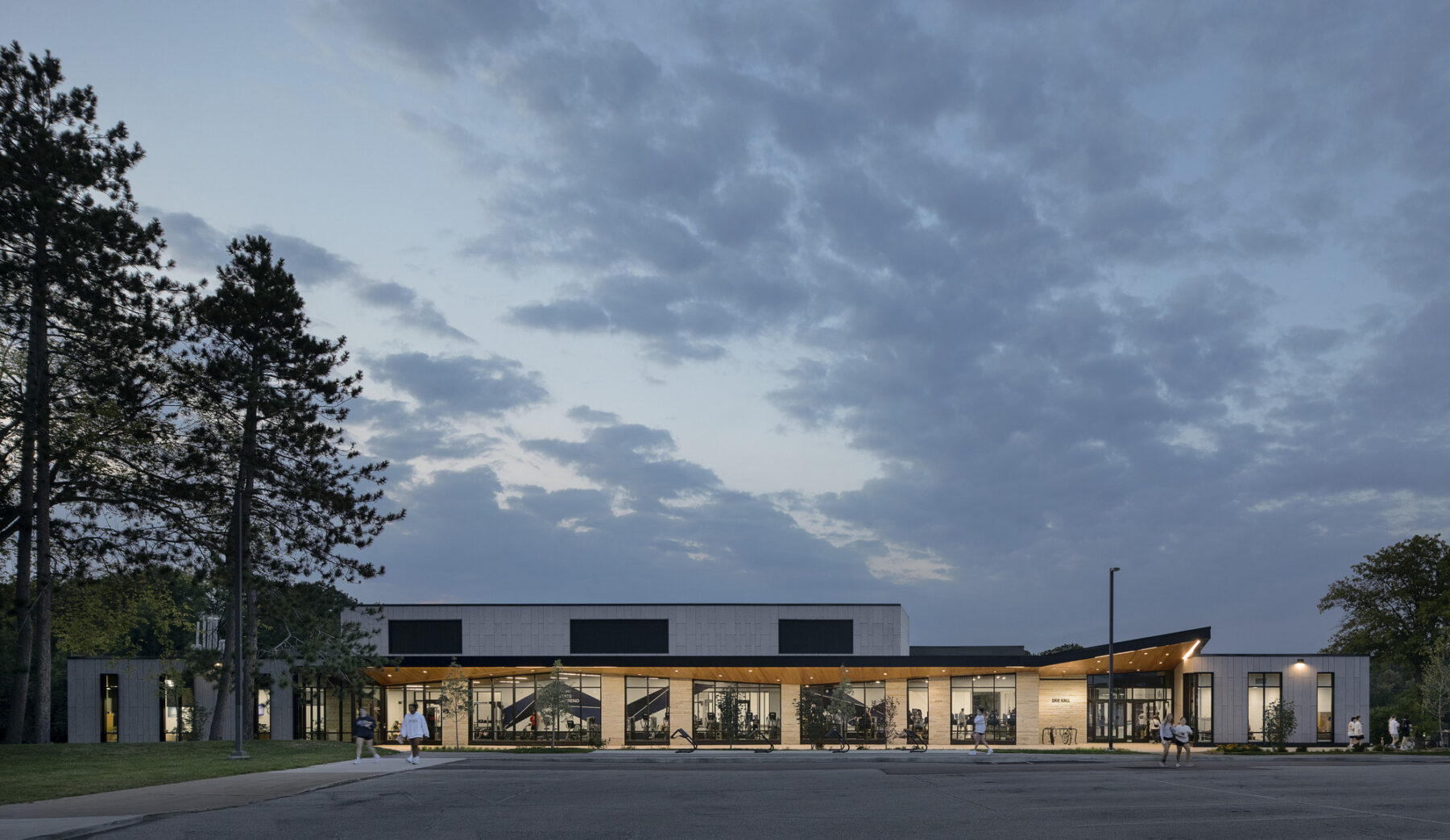 dusk exterior photograph with evening sky and recreation center aglow with light and activitiy