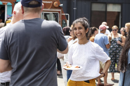 a group of people talking and smiling at a summer barbeque